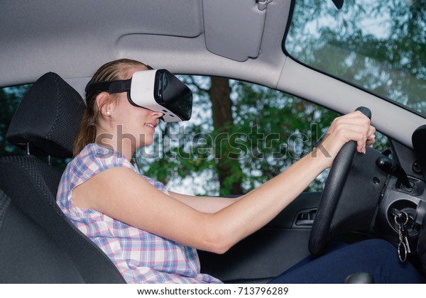 Young female driver using virtual reality\
glasses in car interior