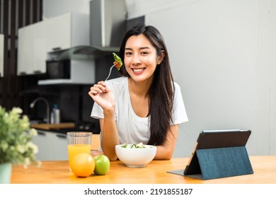 Young female eating organic greens vegetable salad in weight loss diet and wellness on table. Beautiful woman happily eat a healthy salad breakfast in kitchen in the morning. Diet food concept. - Powered by Shutterstock