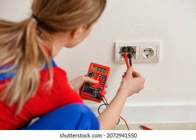 Young Female Electrician Measuring Voltage Of Socket At Home