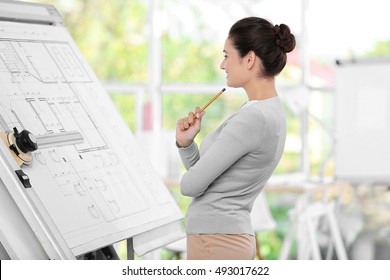 Young female engineer working with project on drawing board in office - Powered by Shutterstock