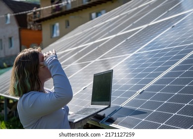 A Young Female Engineer Working With Solar Panels Programs And Optimizing Work Of The Solar Station. A Promising Young Female Engineer Is Setting Up Her Home Solar Power Plant  Green Energy Concept.