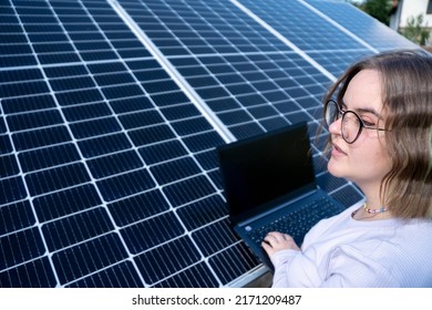 A Young Female Engineer Working With Solar Panels Programs And Optimizing Work Of The Solar Station. A Promising Young Female Engineer Is Setting Up Her Home Solar Power Plant  Green Energy Concept.