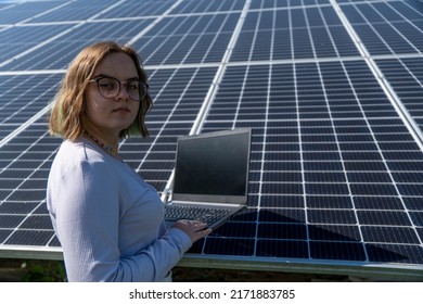 A Young Female Engineer Working With Solar Panels Programs And Optimizing Work Of The Solar Station. A Promising Young Female Engineer Is Setting Up Her Home Solar Power Plant  Green Energy Concept.