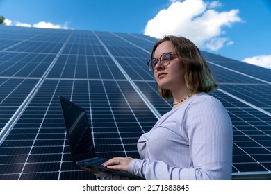 A Young Female Engineer Working With Solar Panels Programs And Optimizing Work Of The Solar Station. A Promising Young Female Engineer Is Setting Up Her Home Solar Power Plant  Green Energy Concept.