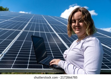 A Young Female Engineer Working With Solar Panels Programs And Optimizing Work Of The Solar Station. A Promising Young Female Engineer Is Setting Up Her Home Solar Power Plant  Green Energy Concept.