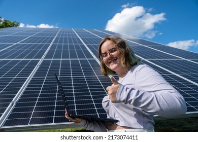 A Young Female Engineer Working With Solar Panels Programs And Optimizing Work Of The Solar Station. A Promising Young Female Engineer Is Setting Up Her Home Solar Power Plant  Green Energy Concept.