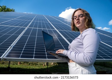 A Young Female Engineer Working With Solar Panels Programs And Optimizing Work Of The Solar Station. A Promising Young Female Engineer Is Setting Up Her Home Solar Power Plant  Green Energy Concept.