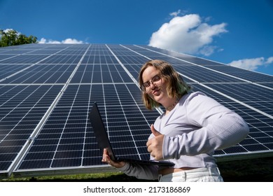 A Young Female Engineer Working With Solar Panels Programs And Optimizing Work Of The Solar Station. A Promising Young Female Engineer Is Setting Up Her Home Solar Power Plant  Green Energy Concept.