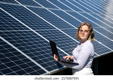 A Young Female Engineer Working With Solar Panels Programs And Optimizing Work Of The Solar Station. A Promising Young Female Engineer Is Setting Up Her Home Solar Power Plant  Green Energy Concept.