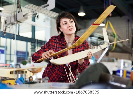Young female enjoying her hobby - creating light airplanes in aircraft hangar