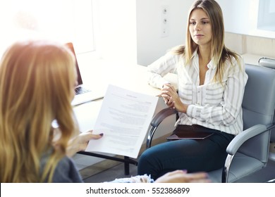 Young female entrepreneur listening to administrative manager report about development of companies advertising marketing using digital gadgets laptop computer connected to inernet in coworking office