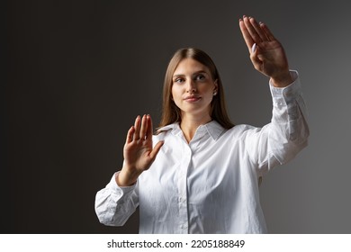 Young female entrepreneur touching virtual screen against grey studio background - Powered by Shutterstock