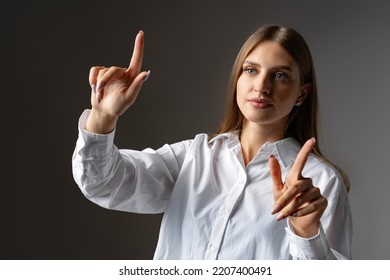 Young female entrepreneur touching virtual screen against grey studio background - Powered by Shutterstock