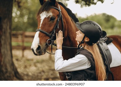 A young female equestrian stands near her horse and prepares for a competition. Show jumping training. Love for horses. - Powered by Shutterstock