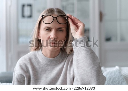 young female with eyeglasses looking at camera squinting eyes, having bad sight and feeling discomfort, poor eyesight concept
