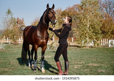 Young female farmer taking care about horse on ranch on summer day, copy space. Girl and brown horse outdoors - Powered by Shutterstock