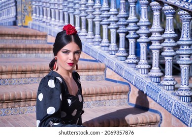 Young Female Flamenco Artist, Hispanic And Brunette, In Typical Black Flamenco Dance Suit With White Polka Dots, Sitting On A Ladder. Flamenco Concept, Dancer, Dancer, Typical Spanish Dance.