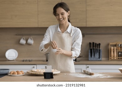 Young female food blogger record video for channel followers, prepare pizza, share cooking knowledge and Italian cuisine recipe secrets with internet audience subscribers, talk to smartphone camera - Powered by Shutterstock