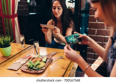 Young Female Food Bloggers Photographing Their Lunch With Smartphones In Restaurant