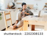Young female freelancer in the kitchen taking a coffee break while working remotely on a laptop.