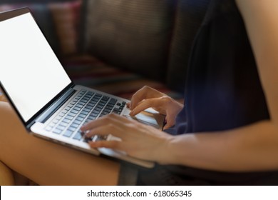 Joven trabajadora independiente trabajando en su laptop sentada en un cómodo sofá. Concepto de trabajo moderno.