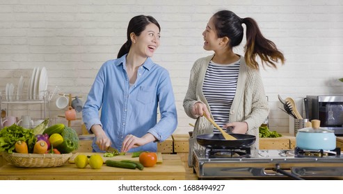 Young Female Friends In Kitchen Cooking Together Vegetarian Meal. Preparing Fruit Salad Healthy Food In Morning Kitchen. Happy Asian Women Singing Dancing And Having Fun While Cutting And Frying