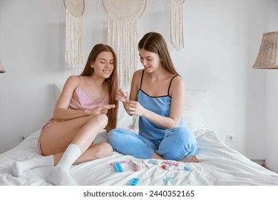 Young female friends painting nails enjoying beauty procedure together - Powered by Shutterstock