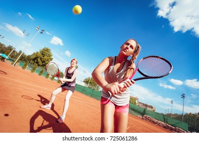 Young female friends playing doubles tennis match. Selective focus.