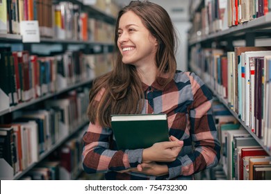 Young female girl  student smiling with book in library