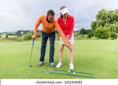 Young Female Golf Player At Driving Range With A Golf Coach