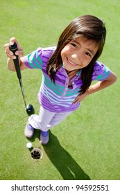 Young female golf player standing next to the hole