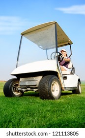Young female golfer driving golf cart