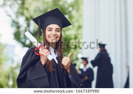 A young female graduate against the background of university graduates.