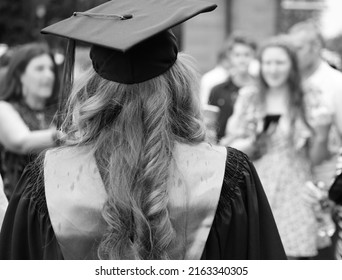 Young Female Graduate With Family At School Graduation.