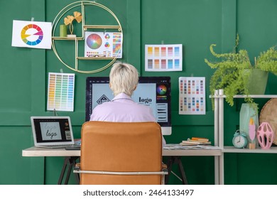 Young female graphic designer working at table in office, back view - Powered by Shutterstock