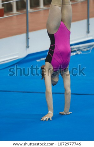 Young female gymnast doing a handstand at the stadium