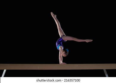 Young Female Gymnast Performing Handstand On Balance Beam, Side View