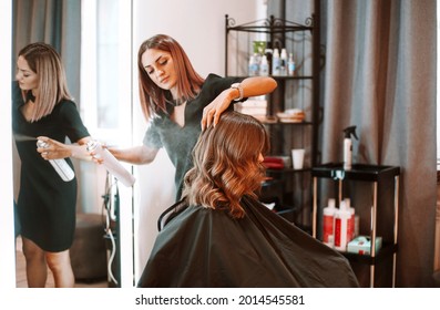 Young female hairdresser fixing hair of gorgeous smiling woman with hairspray. Hairdress and beauty concept - Shutterstock ID 2014545581