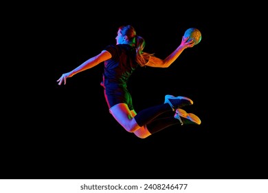 Young female handball athlete practicing throws and receptions against black background in neon light. Energetic and focused training session. Concept of professional sport, dynamic, championship. Ad - Powered by Shutterstock