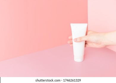 Young Female Hands Holding Blank White Squeeze Bottle Plastic Tube On Pink Background. Packaging Of Cream, Lotion, Gel, Facial Foam Or Skincare. Cosmetic Beauty Product Branding Mock-up. Copy Space.