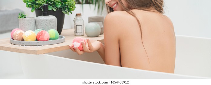 Young female hands holding pink bath bomb. Luxury cosmetics and skincare concept. Copy space