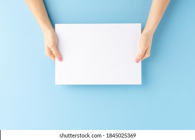 Young female hands showing empty white paper sheet on blue background. Mockup - Shutterstock ID 1845025369