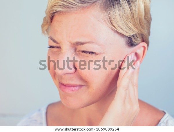 young female having ear pain touching her painful\
head earache