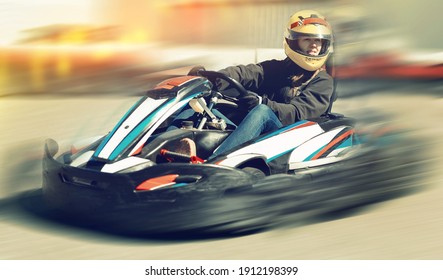 Young female in helmet driving car for karting in sport club outdoor