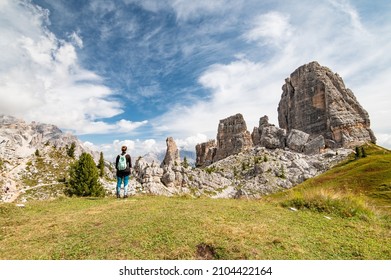 Young female hiker standing and looking at Cinque Torri view from Rifugio Scoiattoli (refuge). Dolomites, Trentino Alto Adige region, South Tyrol, Italy, Europe.
