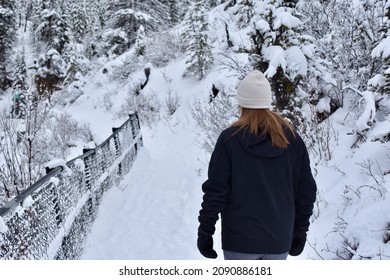 Young Female Hiking On Snowy Winter Trail In The Forest