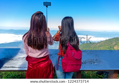 Young female hipster using smartphone with blue sky background