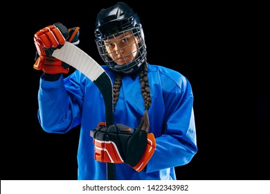 Young female hockey player isolated on black background. Sportswoman wearing equipment and helmet standing with the stick. Concept of sport, healthy lifestyle, motion, movement, action. - Powered by Shutterstock