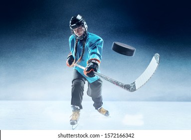 Young female hockey player with the stick on ice court and blue background. Sportswoman wearing equipment and helmet practicing. Concept of sport, healthy lifestyle, motion, movement, action. - Powered by Shutterstock