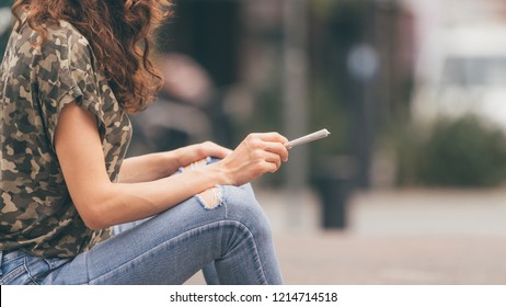 Young female holding a marijuana joint in her hand, ready to smoke. Urban weed smoking.
